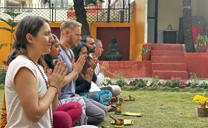 Participants engaged in a meditation session using singing bowls in a garden setting.